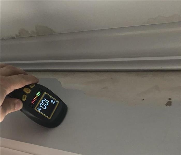 moisture meter being used on a wall that has water damage.